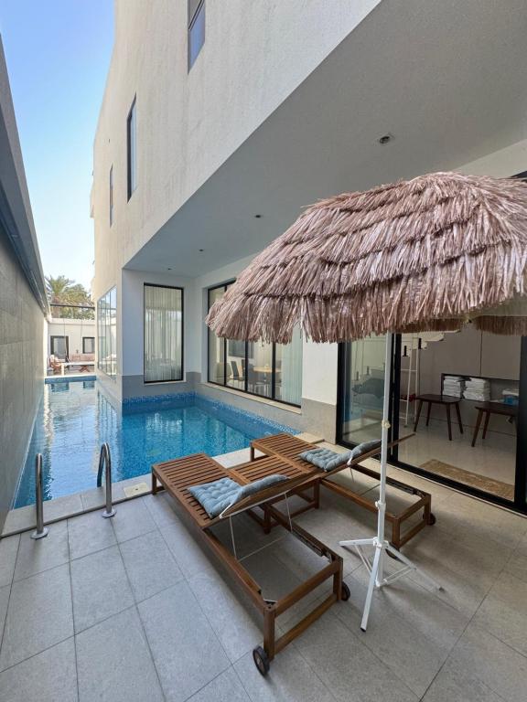 a swimming pool with a large straw umbrella and a table at شاليهات روح الخبر in Al Khobar