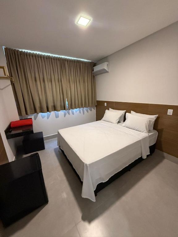 a bedroom with a large white bed and a window at JBR Park Hotel in Goiânia
