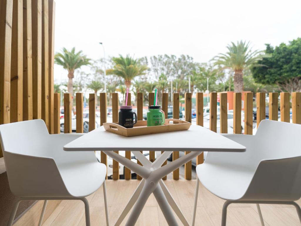 ein weißer Tisch und zwei weiße Stühle auf einer Terrasse in der Unterkunft Sunset Arguineguin by CanariasGetway in Arguineguín