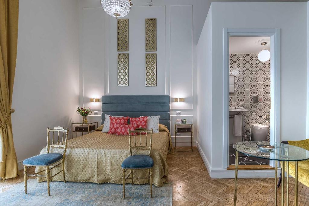 ローマにあるイングラミ スイーツ アンド スパのベッドルーム1室(ベッド1台、椅子2脚、テーブル付)