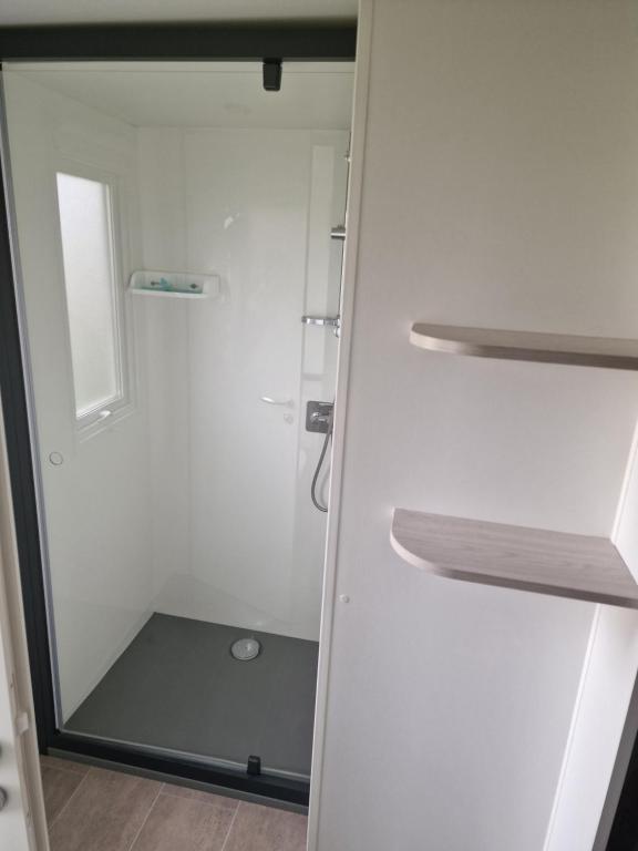 a bathroom with a shower with a glass door at TRIGANO Savina 2022 in Litteau