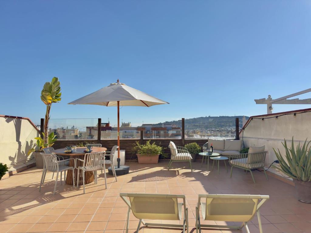 a patio with chairs and tables and an umbrella at Atic Barcelona in Barcelona