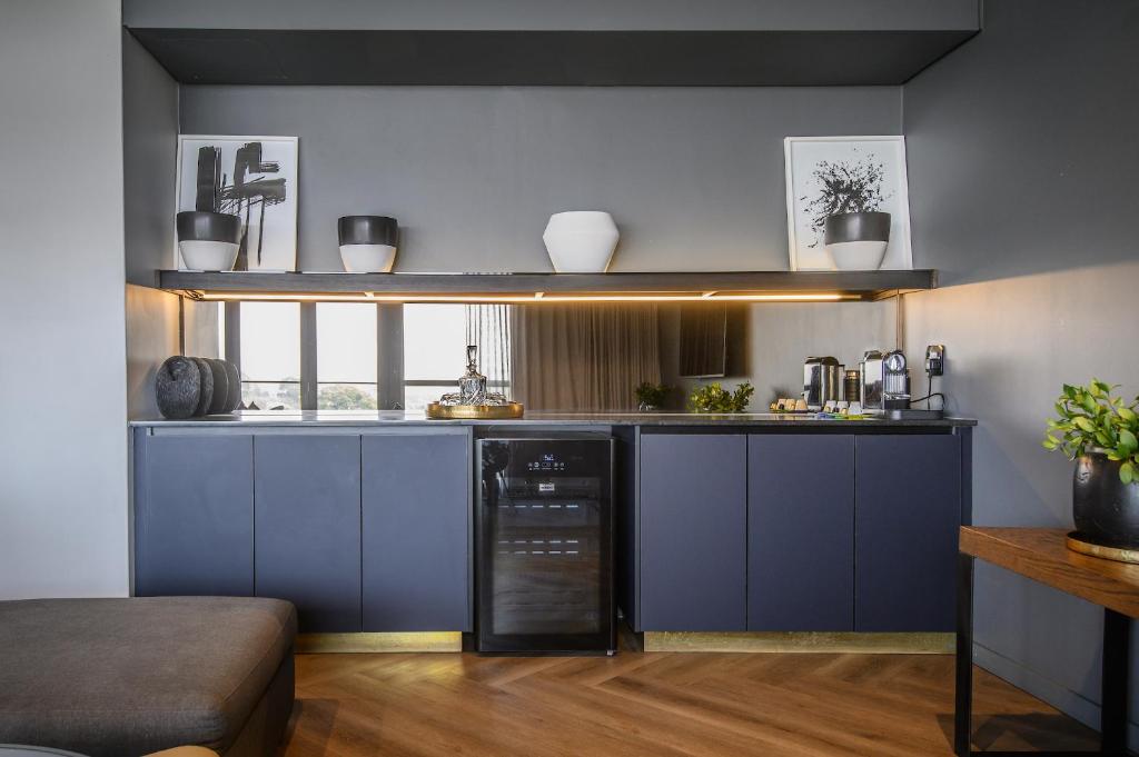 a kitchen with blue cabinets and a black dishwasher at The Capital Boardwalk in Gqeberha