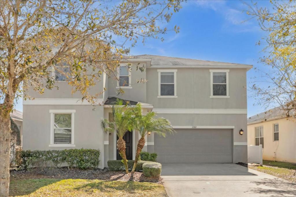 a white house with a driveway and trees at 5 Bedrooms 5 Bathrooms Crystal Cove 1042Td in Kissimmee