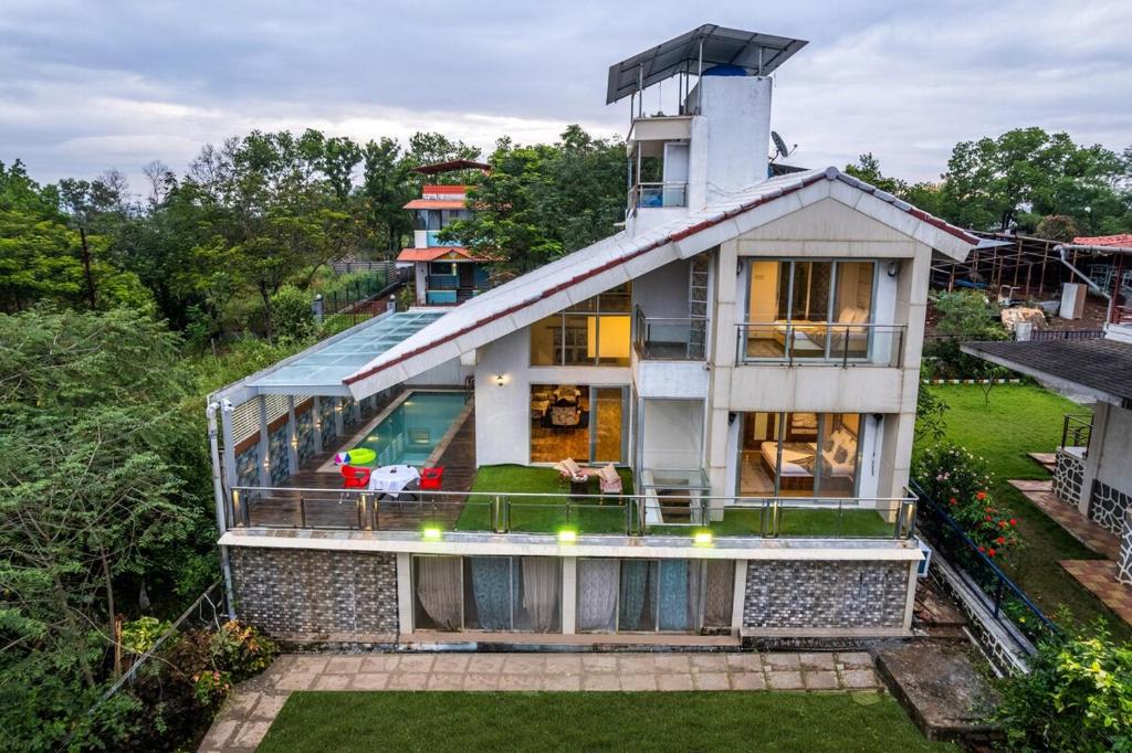 an image of a house with a glass facade at Gauri Villa by ELIVAAS 3-BHK Villa With Private Pool, Lounge, Garden & Bathtub With 360 Panoramic Hill Views Near Waterfalls in Kasāra