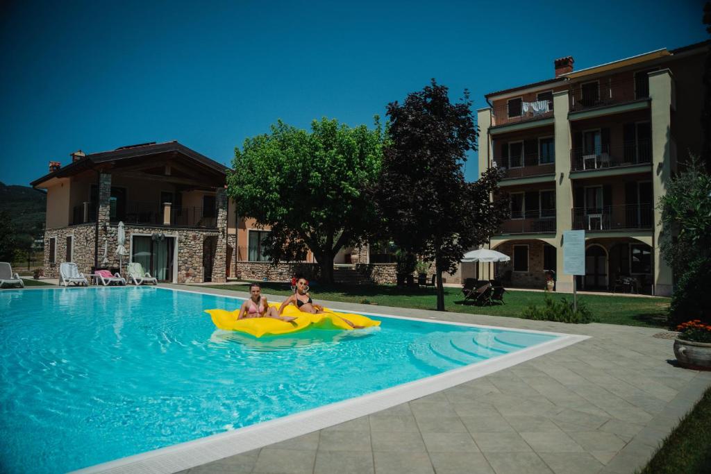 zwei Personen in einem aufblasbaren Floß in einem Schwimmbad in der Unterkunft Residence Rustico in Garda