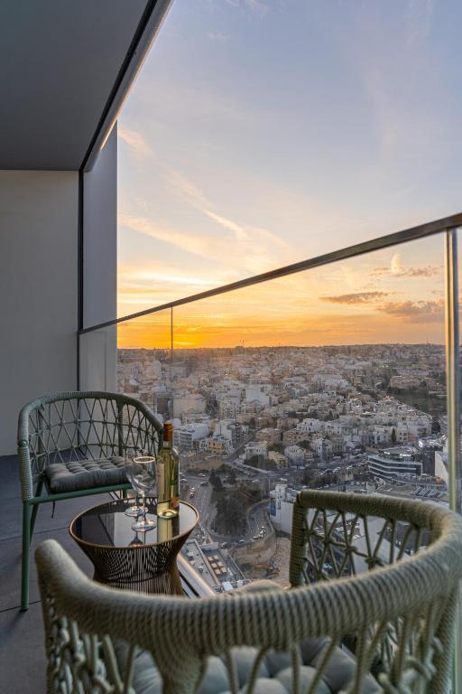 a balcony with a table and chairs and a view of a city at 21st Floor Sunset Apartment - Mercury Tower with Pool Access by Stays Uniq in St. Julianʼs