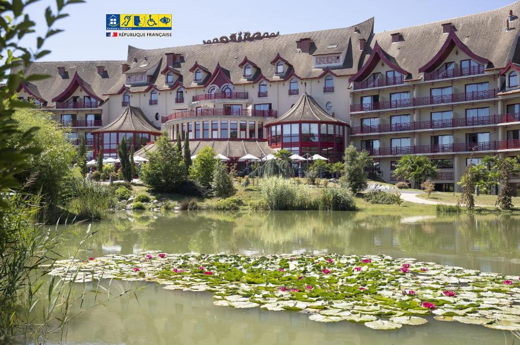 a hotel with a pond with flowers in front of it at Les Pagodes de Beauval in Saint-Aignan