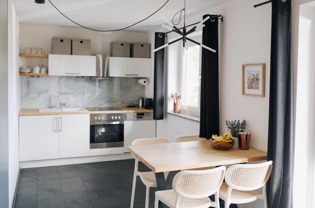 une cuisine avec des armoires blanches et une table et des chaises en bois dans l'établissement Schöne Designer-Wohnung im Mangfalltal, à Bruckmühl