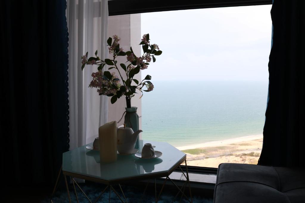 a vase with flowers on a table in front of a window at Apec Mui Ne Chill Sea View in Ấp Thiẹn Ái