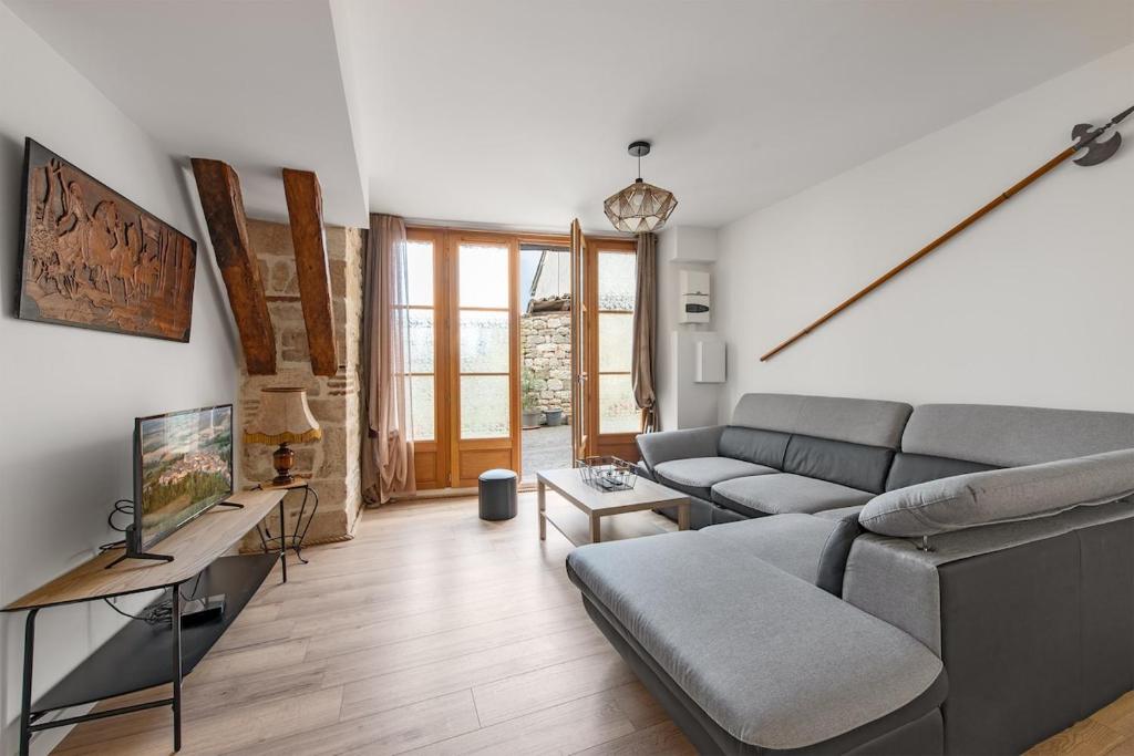 ein Wohnzimmer mit Sofa und Fernseher in der Unterkunft Le Loft du Castel Bas - Pause au cœur du Tarn in Castelnau-de-Montmiral