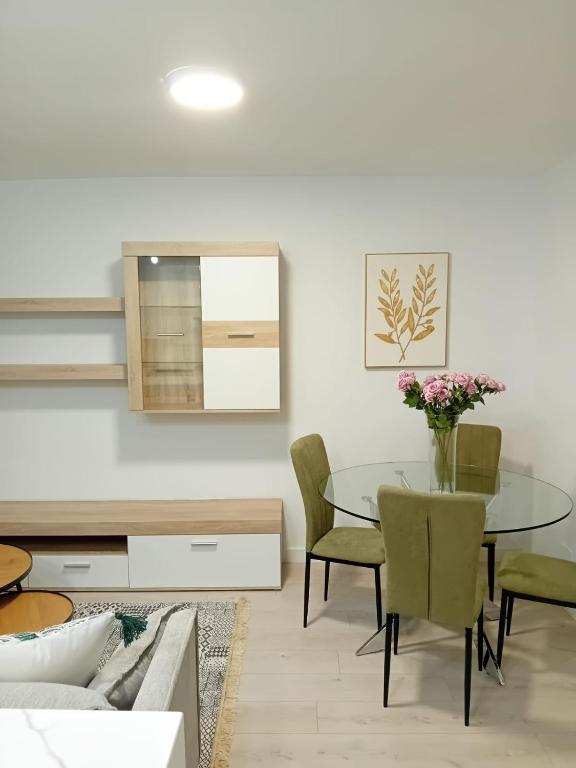 a dining room with a glass table and green chairs at El Rincon de Riera in Pola de Lena