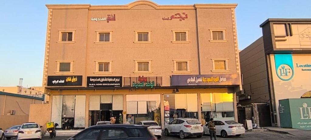 ein Gebäude mit davor geparkten Autos in der Unterkunft نجم الحضارة للشقق المخدومة in Al-Hasa