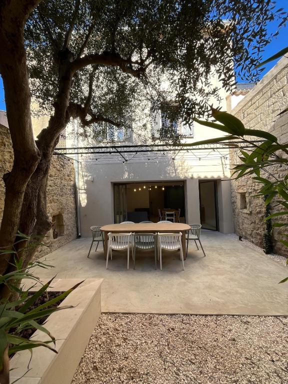 a table and chairs in a courtyard with a tree at Chez Louise et Léo in Aigues-Mortes