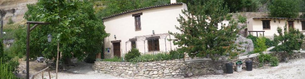 une maison blanche avec un mur en pierre à côté d'un bâtiment dans l'établissement Huerta del Tajo, à Ronda