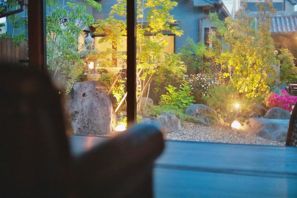 Eine Person zeigt durch ein Fenster auf einen Garten. in der Unterkunft Osakaya Hotel & SAUNA in Kaizuka