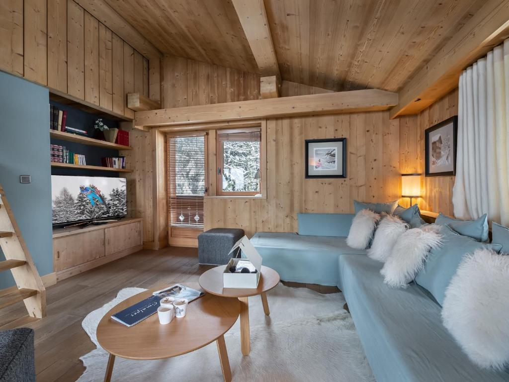 ein Wohnzimmer mit einem blauen Sofa und Holzwänden in der Unterkunft Chalet Familial à Megève avec Espace Bien-Être, 4 Chambres, Près de Rochebrune - FR-1-569-3 in Saint-Germain-et-Mons