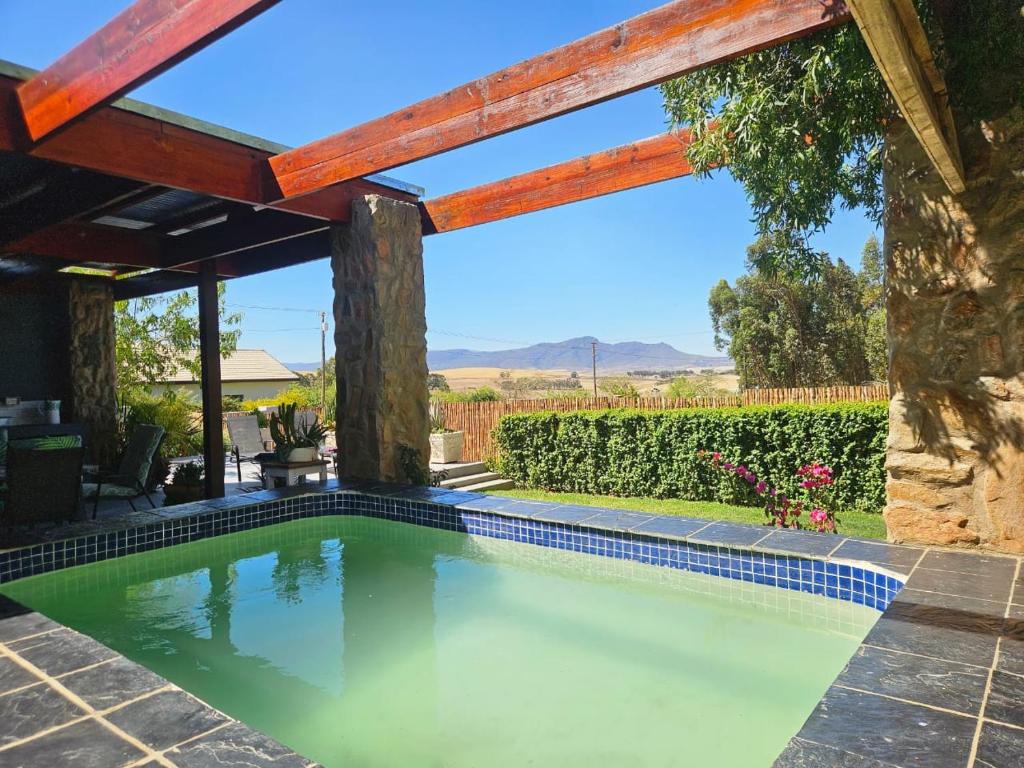 a swimming pool in a backyard with a wooden pergola at The Homestead at Koringberg Country Cottages in Koringberg