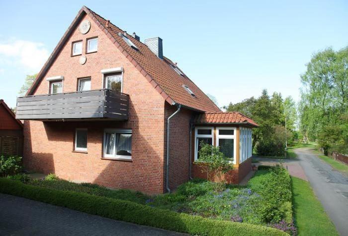 ein rotes Backsteinhaus mit Balkon an einer Straße in der Unterkunft Komfortable Ferienwohnung in Bockhorn mit Großem Balkon - b48718 in Walsrode