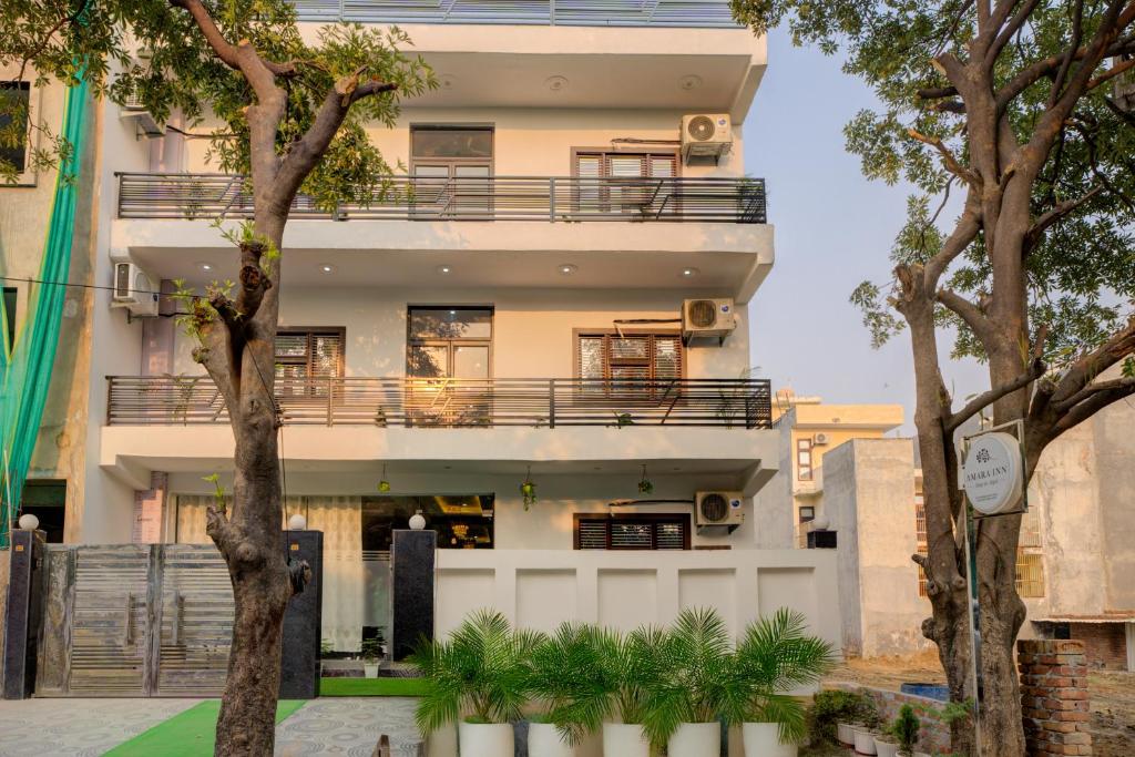 a tall white building with trees in front of it at Amara Inn in Greater Noida