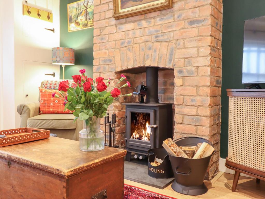 a living room with a fireplace and a table with flowers at Derwen House in Llangollen
