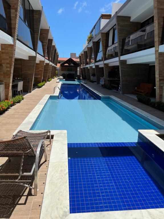 a swimming pool with chairs next to a building at Casa em condomínio na praia in Cabedelo