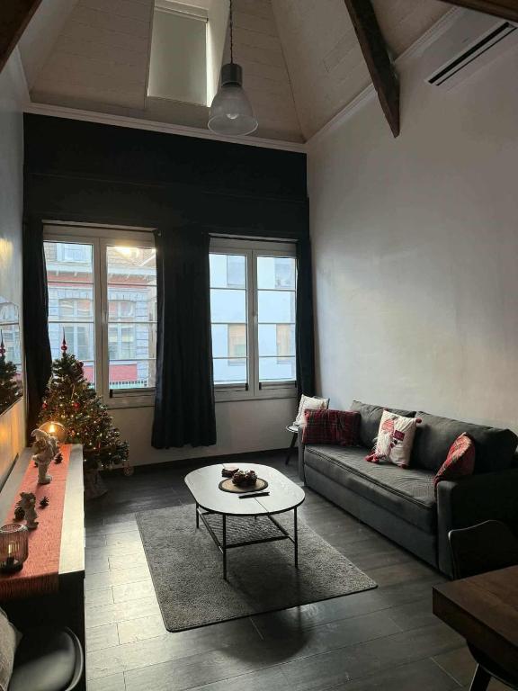 a living room with a couch and a christmas tree at Au bât Tournai Appart in Tournai