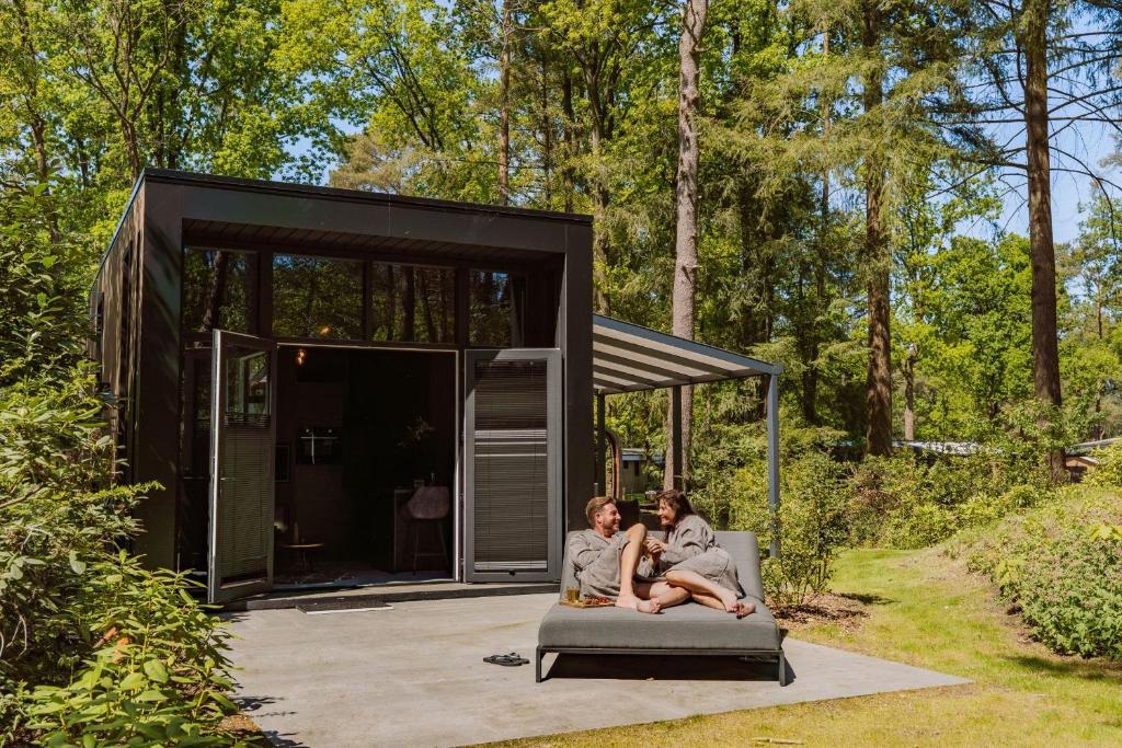 two people sitting on a couch in front of a tiny house at Vakantiepark Samoza in Vierhouten