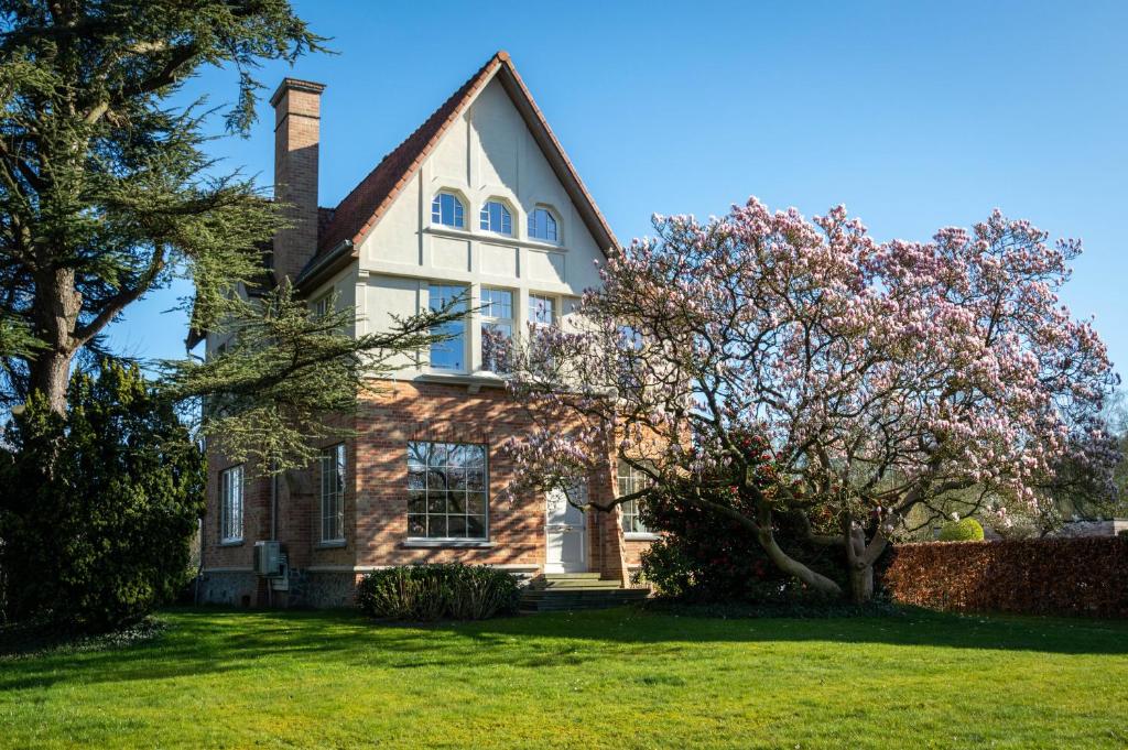 a large brick house with a tree in the yard at Villa Magnolia B&B in Oostkamp