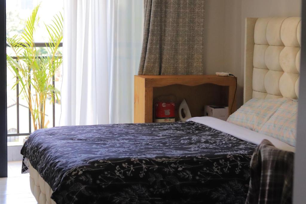 a bedroom with a bed with a blue blanket and a window at Quick Connect Studio Kileleshwa in Nairobi