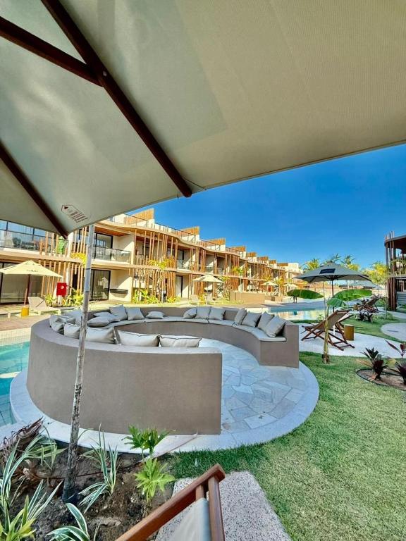 eine Terrasse mit Sofas und Sonnenschirm in einem Ferienresort in der Unterkunft Tatuamunha - River03 - Vila Boutique Naay in Tatuamunha