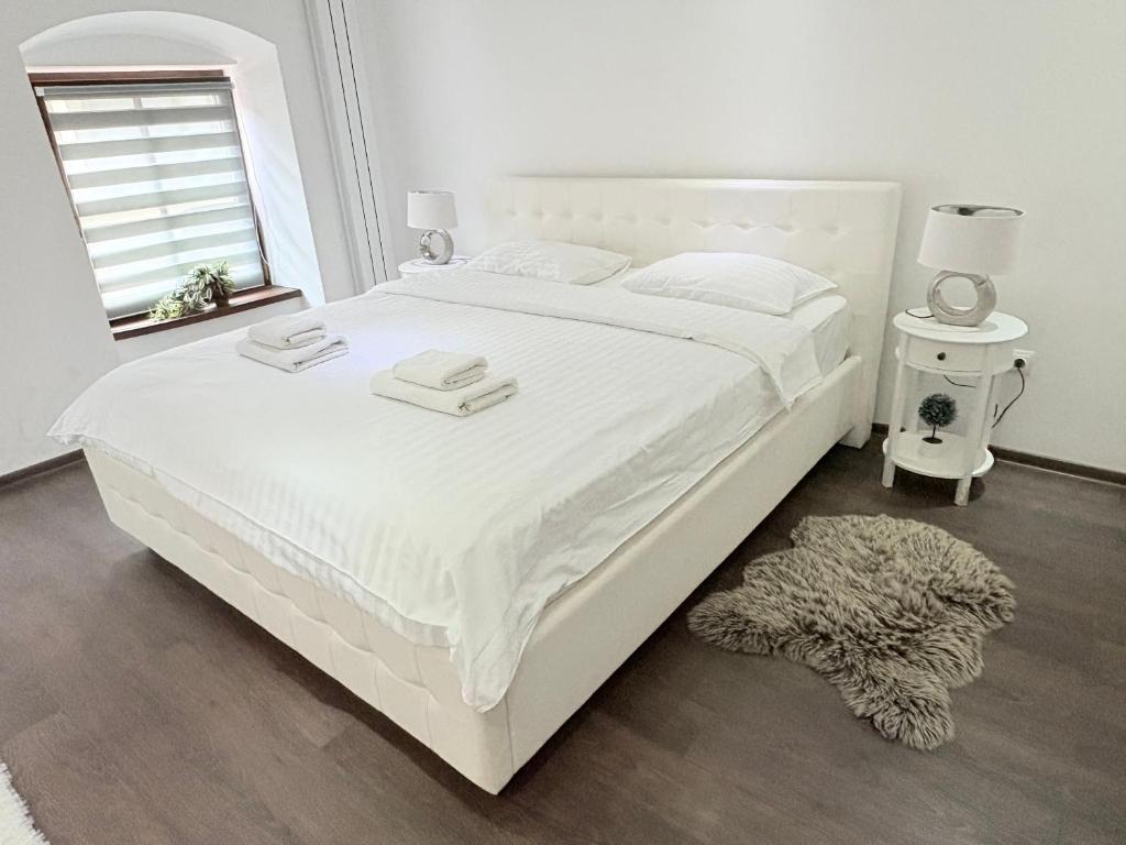 ein Schlafzimmer mit einem großen weißen Bett und einem Teppich in der Unterkunft Old City Poema in Braşov