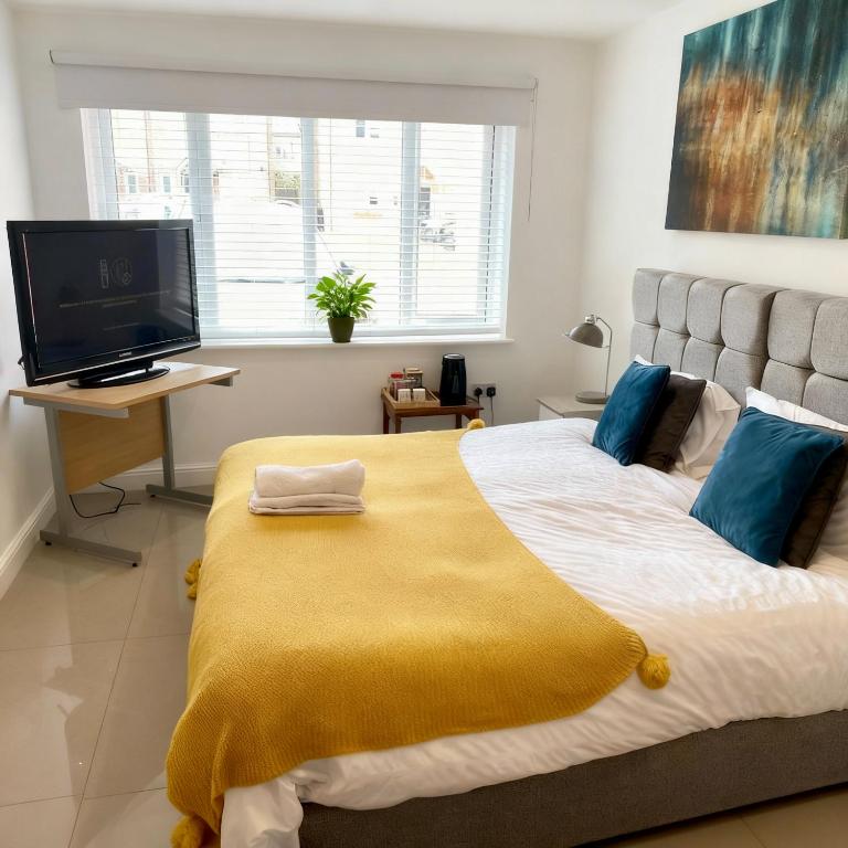 a bedroom with a large bed with a yellow blanket at Flexistay Studio at Watford in Watford