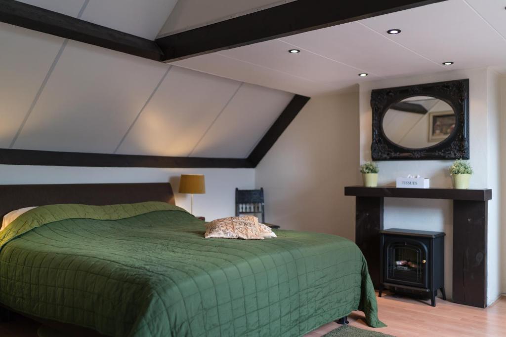 een slaapkamer met een groen bed en een open haard bij Gasterij de Poort in Gulpen