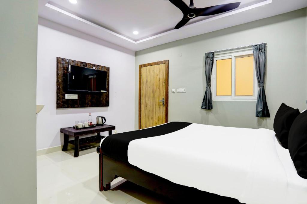 a bedroom with a white bed and a ceiling fan at Hotel O Savoy Grand in Warangal