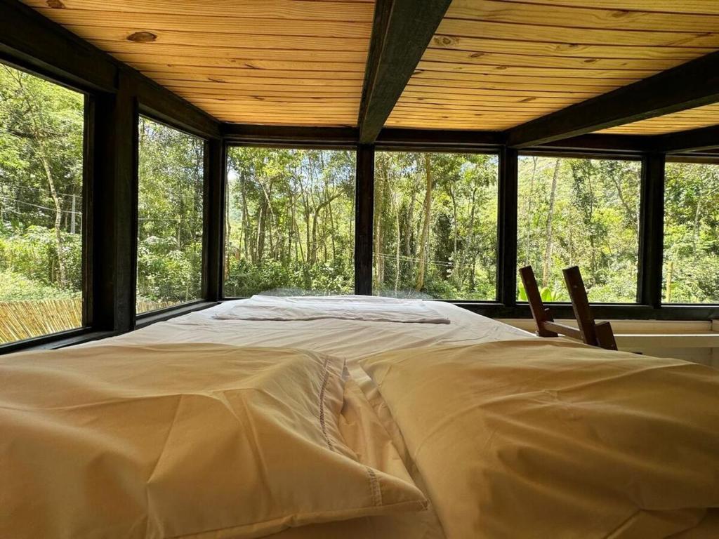 un grand lit dans une chambre avec une grande fenêtre dans l'établissement Cabana em Araras, à Petrópolis