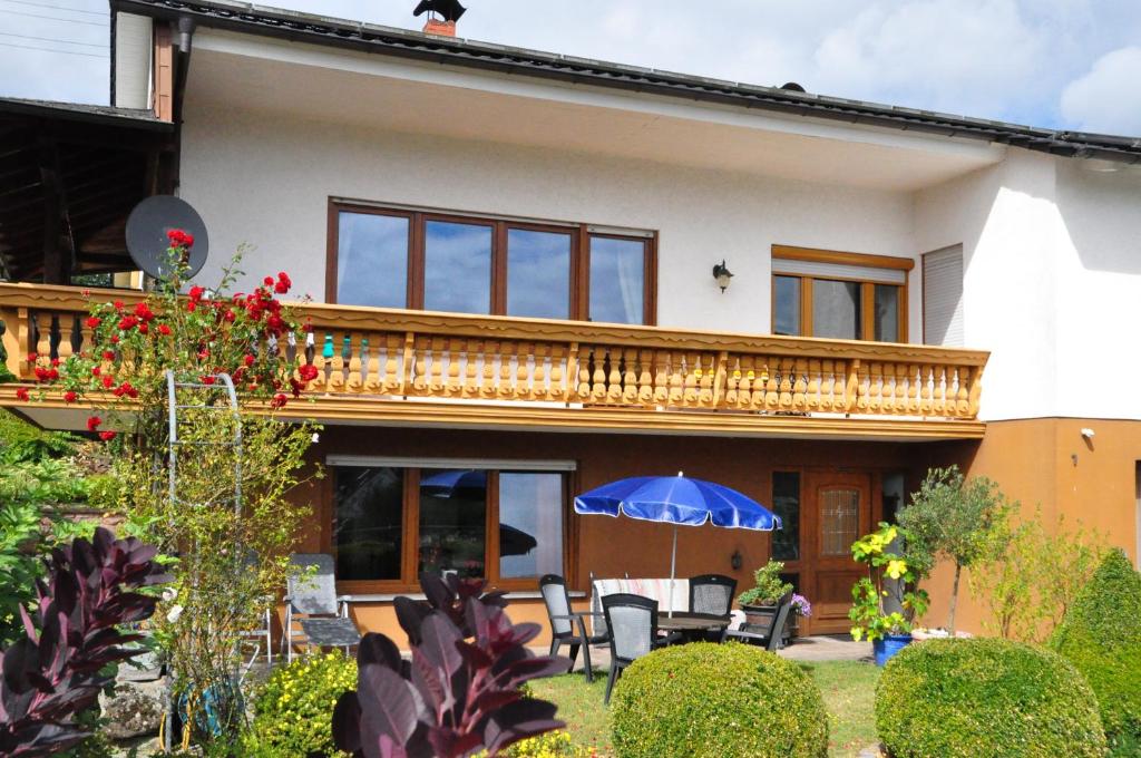 ein Haus mit einem Balkon und einem Tisch mit einem Sonnenschirm in der Unterkunft Ferienwohnung Blick in den Wasgau in Fischbach