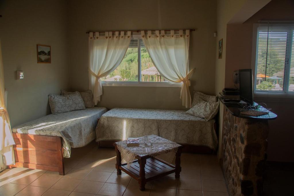 uma sala de estar com duas camas e uma janela em Apart Cabañas El Tala em Bialet Massé