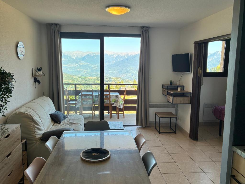 Una sala de estar con una mesa y una gran ventana. en T2 Reallon gardette, en Réallon