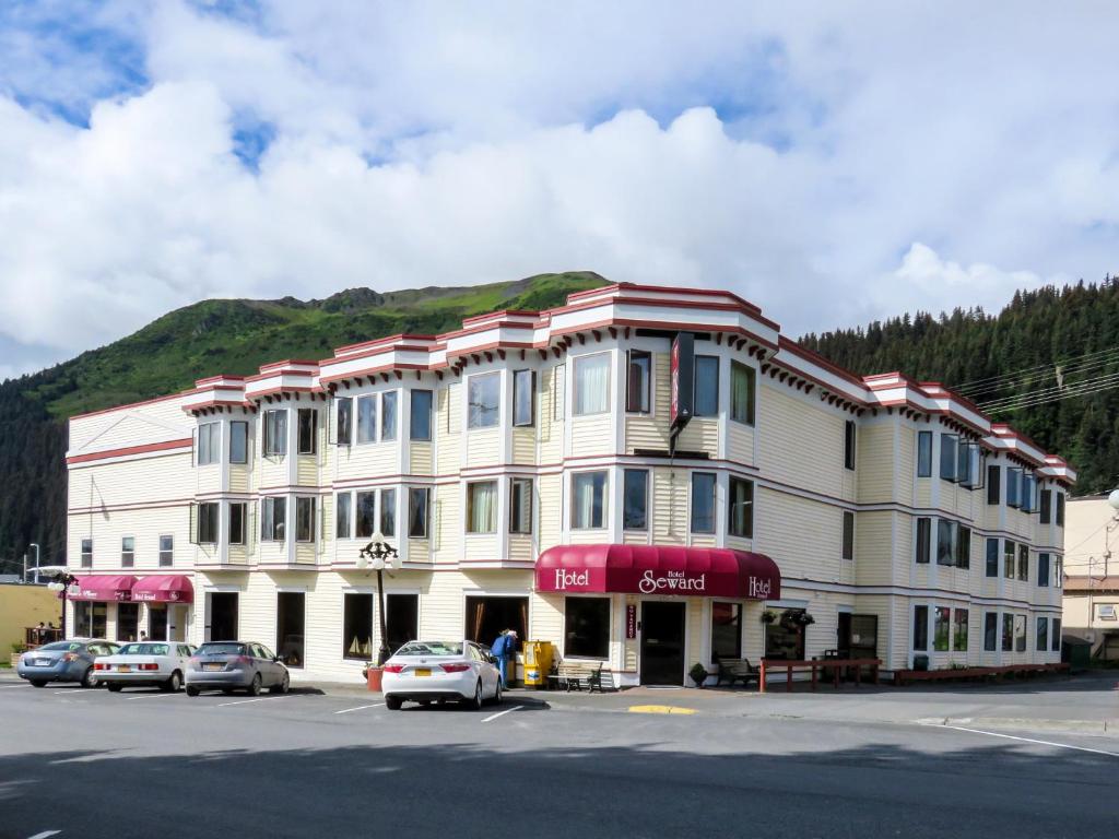 een groot wit gebouw met auto's geparkeerd voor het bij Hotel Seward in Seward