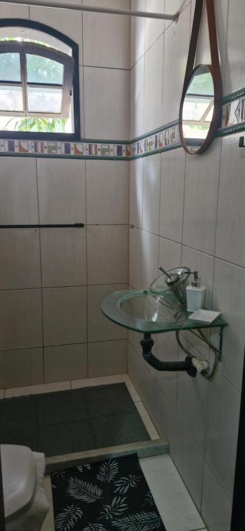 a bathroom with a glass sink and a mirror at Hostel Suite Home in Saquarema