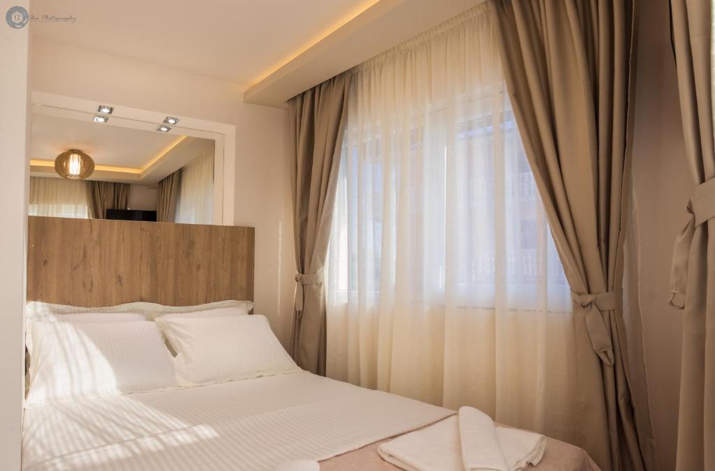 Un dormitorio con una cama blanca y una ventana. en Villa Montemaris Budva, en Budva