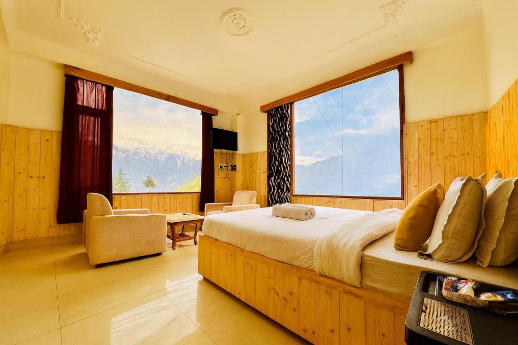 a bedroom with a large bed with a large window at Hotel Suraj Inn ,near Hadimba Devi Temple ! Rooftop Restaurant ! Personal Parking in Manāli