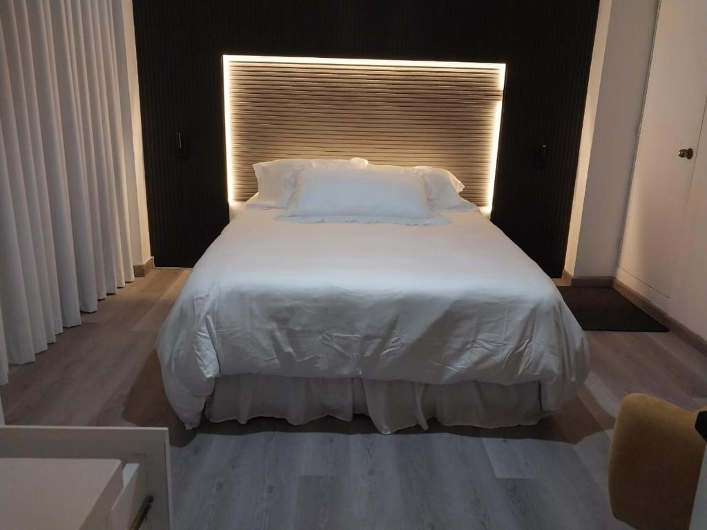 Una cama con sábanas blancas y almohadas en un dormitorio. en Casa Miraflores ARM, en Lima