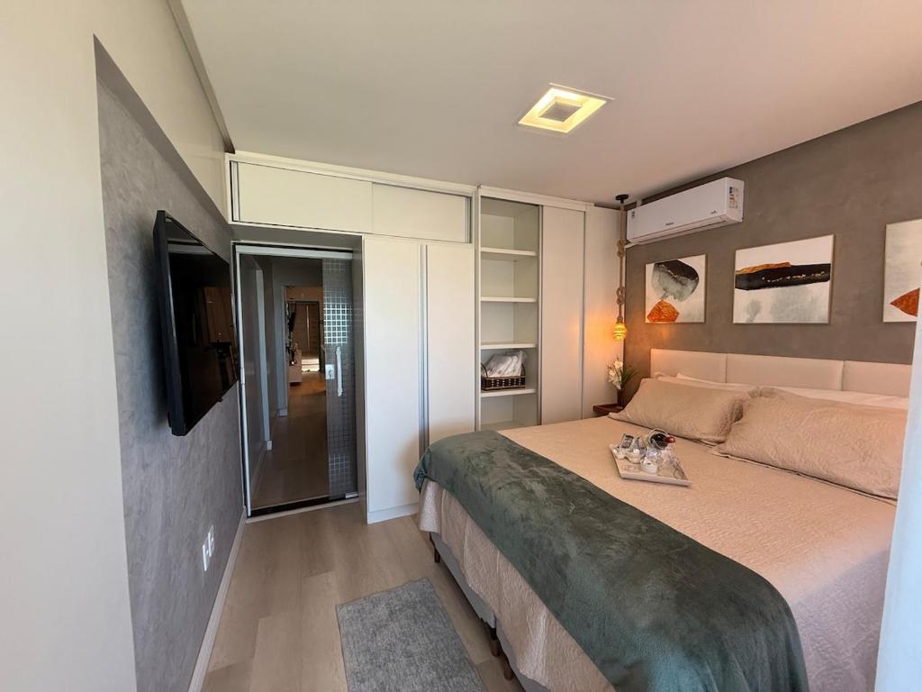 a small bedroom with a bed and a television at Conforto Frente ao Mar - Areia Preta in Guarapari