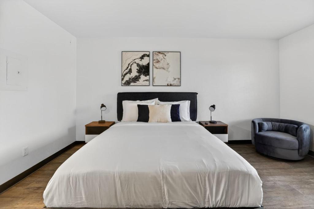 a bedroom with a white bed and a blue chair at Bright modern studio featuring full kitchenette in Las Vegas