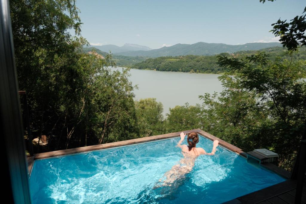 a woman in a swimming pool with a view of a lake at Porto Gumati in Kutaisi