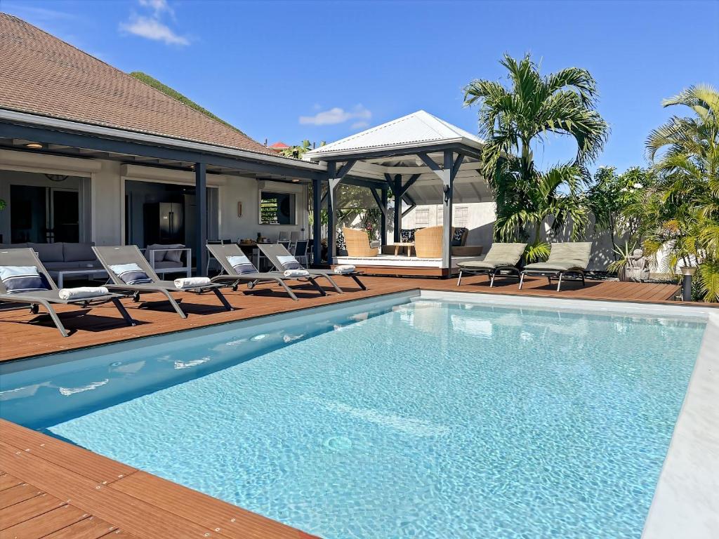 ein Swimmingpool mit Stühlen und ein Haus in der Unterkunft Villa Mangorient 3 bd private pool in Orient Bay in Orient Bay