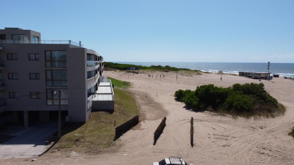 a building on a beach next to a beach at Jade Residencias de Mar in Villa Gesell
