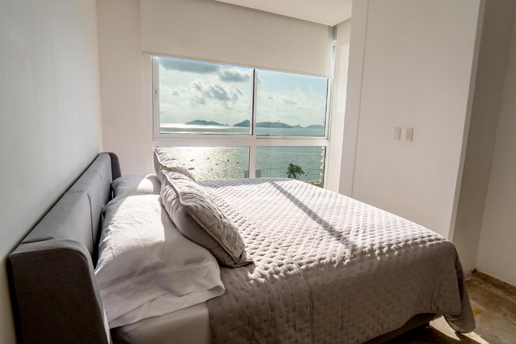 un lit dans une chambre avec une grande fenêtre dans l'établissement Departamento para 12 personas con vista al mar, à Acapulco
